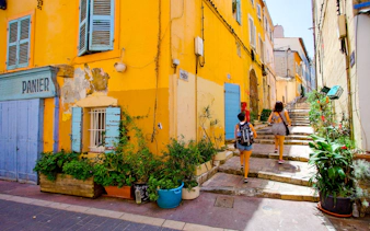 Colorful street in Le Panier, Marseille with people walking up stone steps.