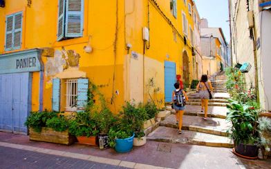 Colorful street in Le Panier, Marseille with people walking up stone steps.