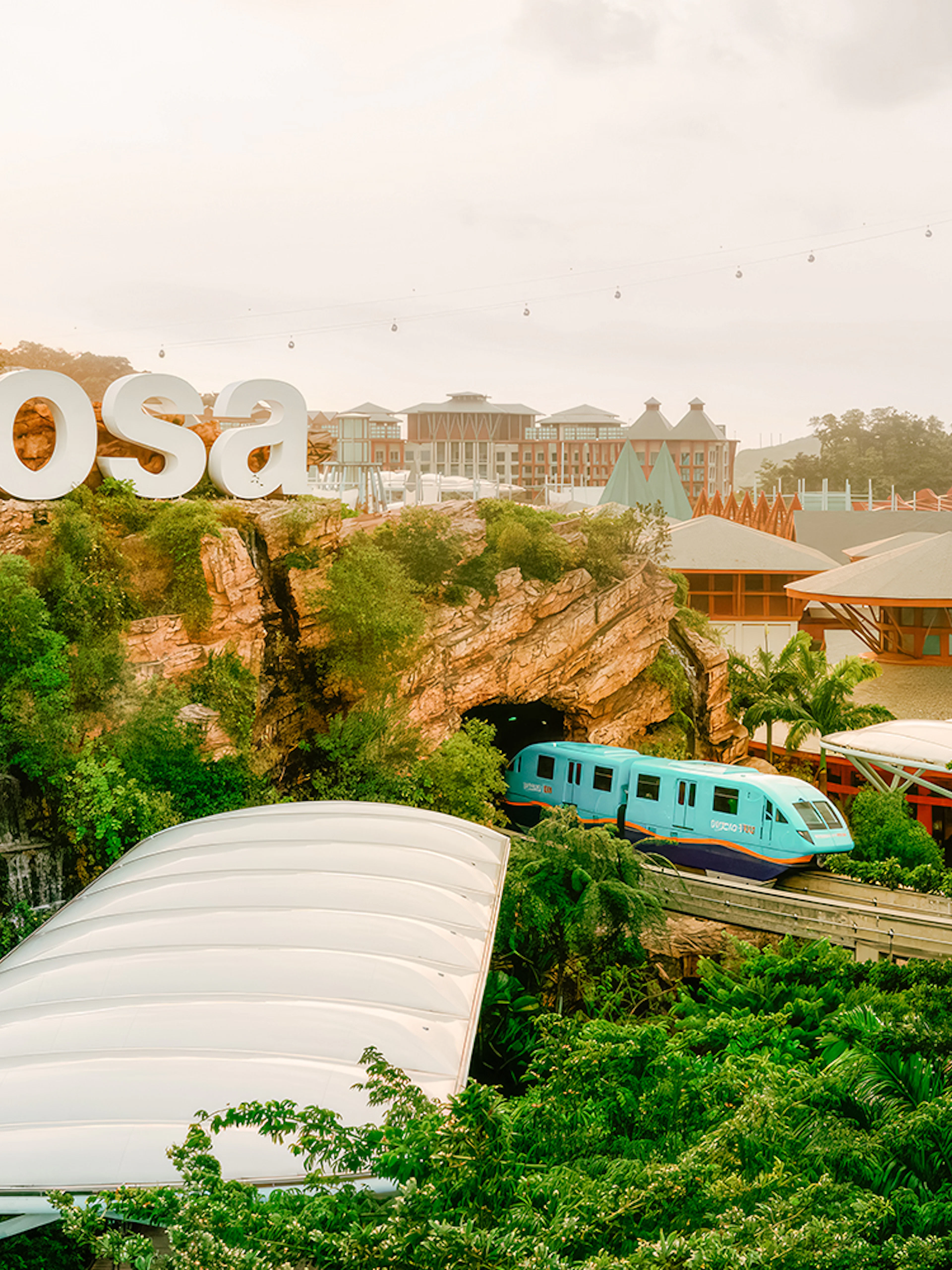 Monorail passing through lush greenery on Sentosa Island, Singapore.