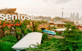 Monorail passing through lush greenery on Sentosa Island, Singapore.