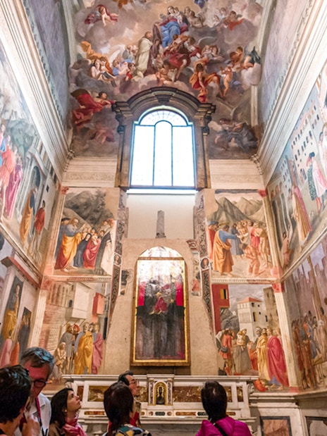 Frescoes in the Brancacci Chapel depicting Renaissance art with visitors observing.
