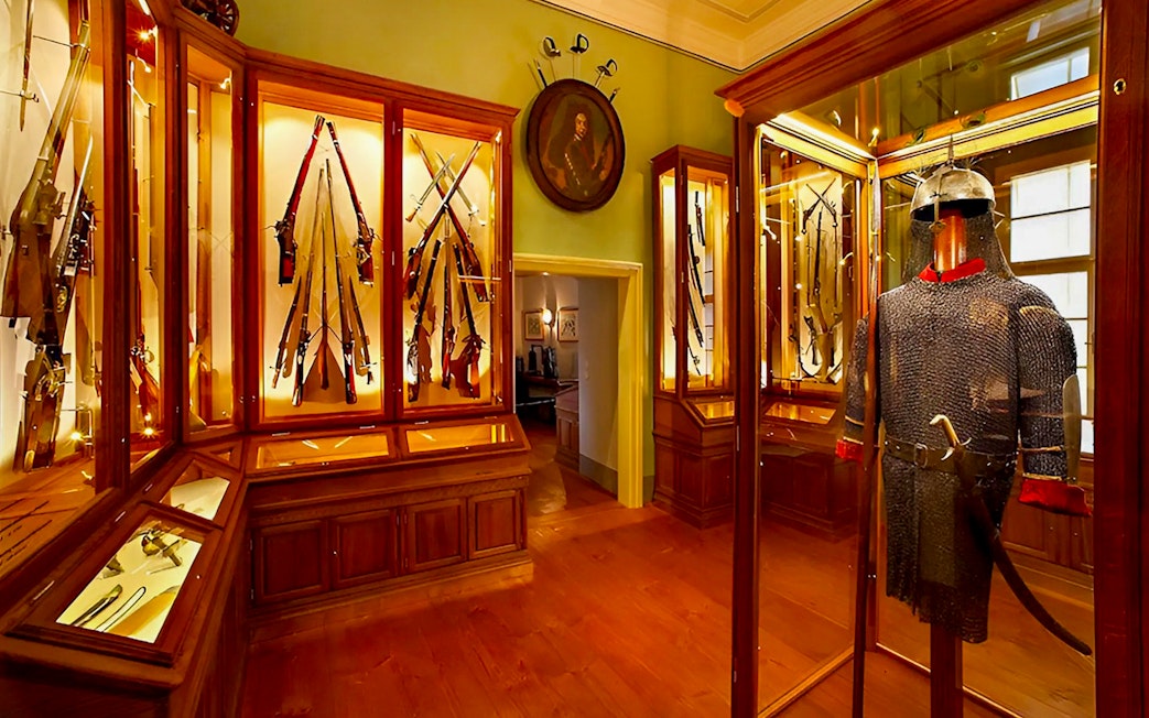 Cesky Krumlov Castle Museum interior with medieval armor and weaponry display.