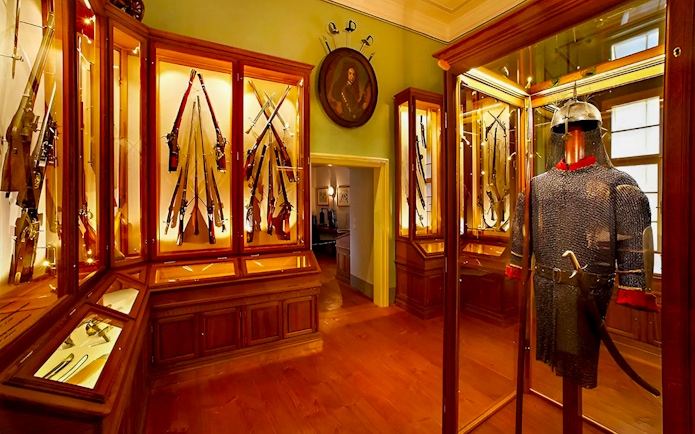 Cesky Krumlov Castle Museum interior with medieval armor and weaponry display.
