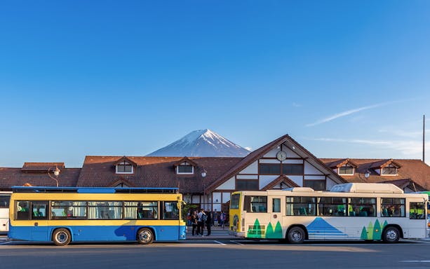Buses parked in front of a station with Mt. Fuji in the background, Japan.