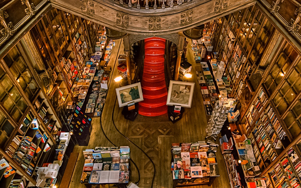 Top view of Lello Library's red staircase surrounded by bookshelves in Porto, Portugal.