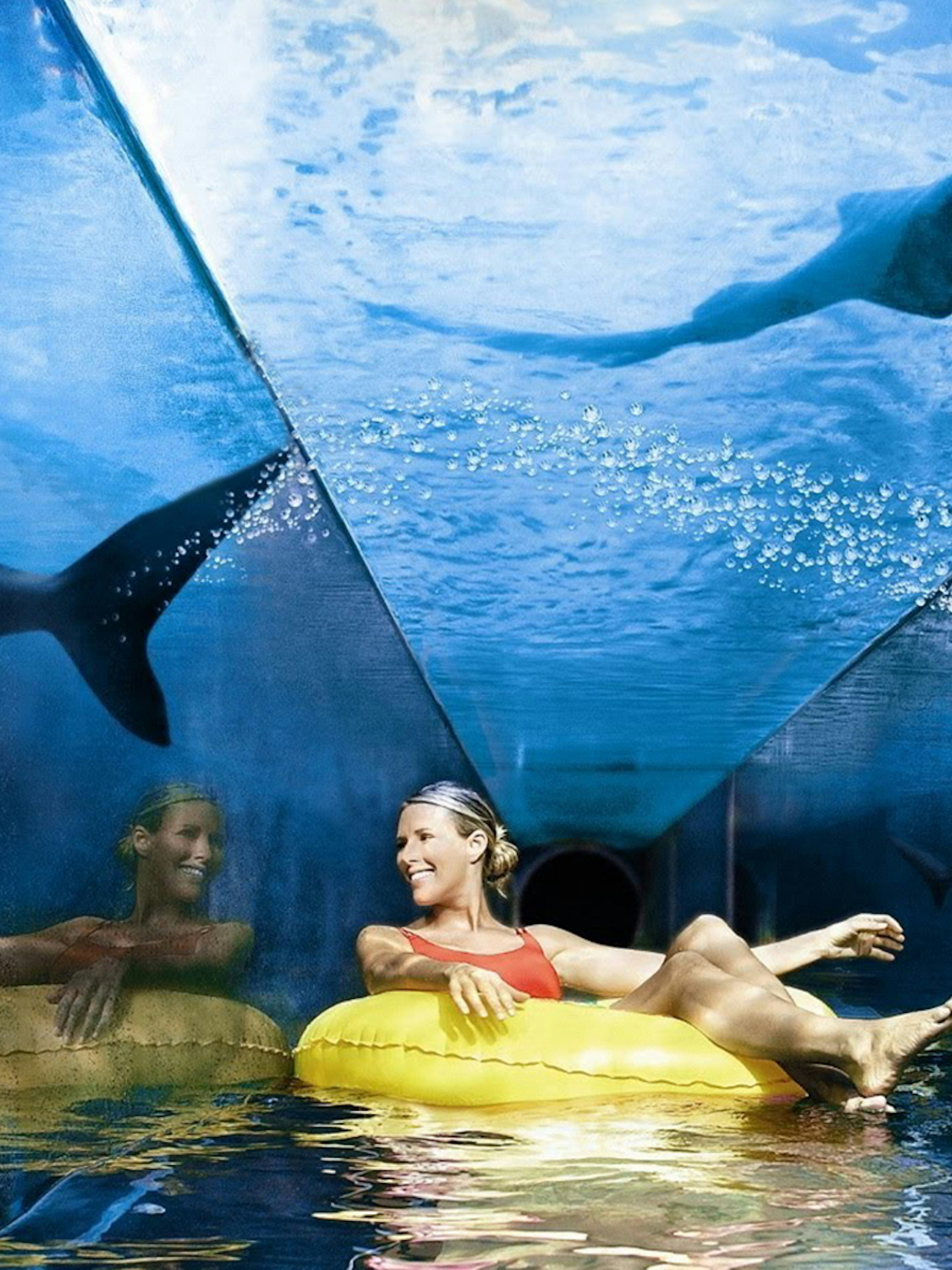 Tourist on a yellow float in a shark tunnel at Aquaventure Waterpark, Dubai.