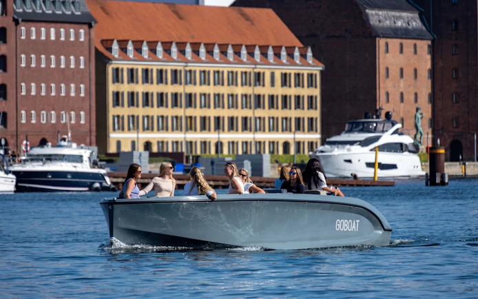 Sightseeing boat with tourists on a canal in front of historic buildings.