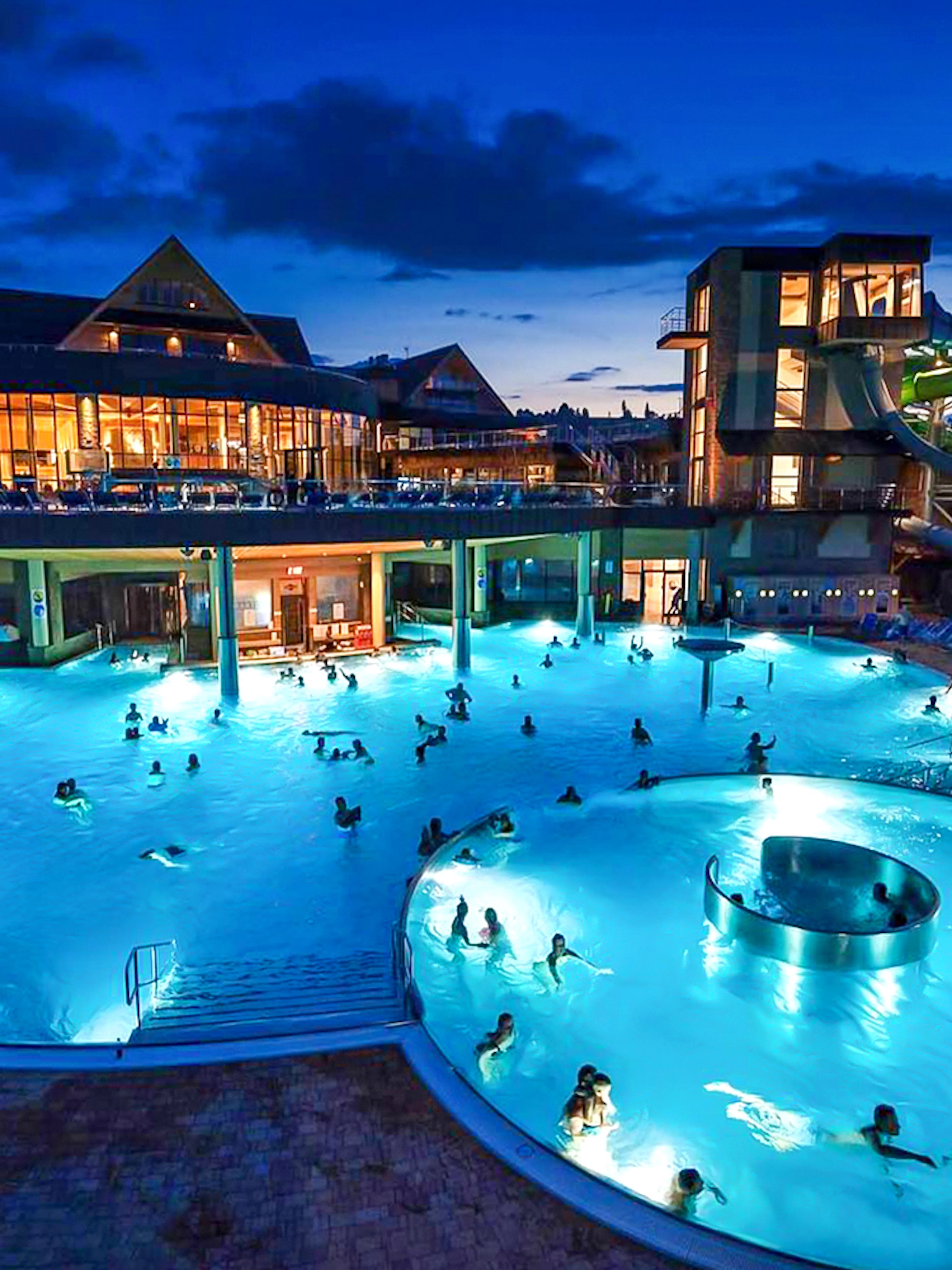 Zakopane Thermal Bath at night with illuminated pools and water slides.
