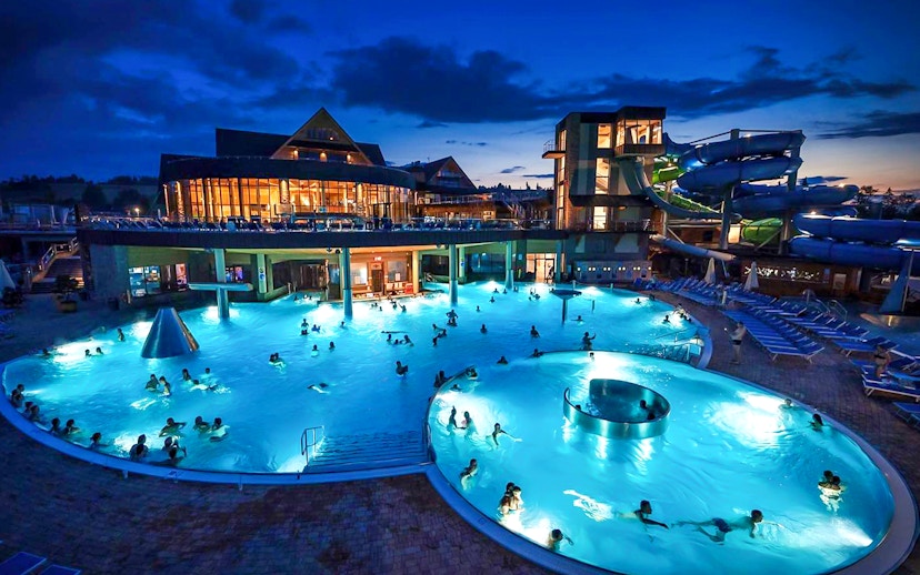 Zakopane Thermal Bath at night with illuminated pools and water slides.