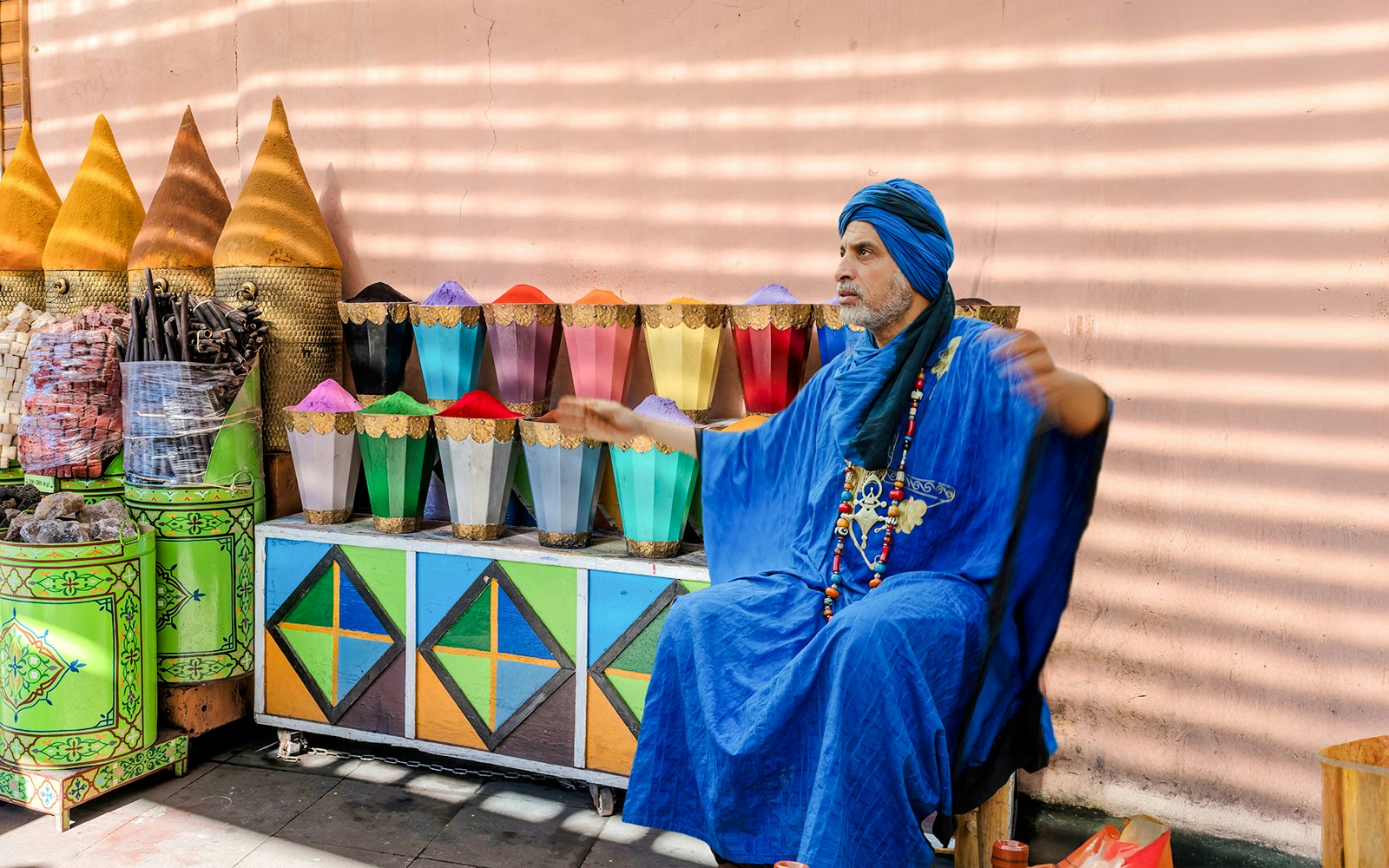 Man in blue robe at spice stall in Marrakesh Medina Souks.