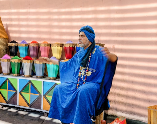 Man in blue robe at spice stall in Marrakesh Medina Souks.