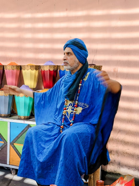 Man in blue robe at spice stall in Marrakesh Medina Souks.