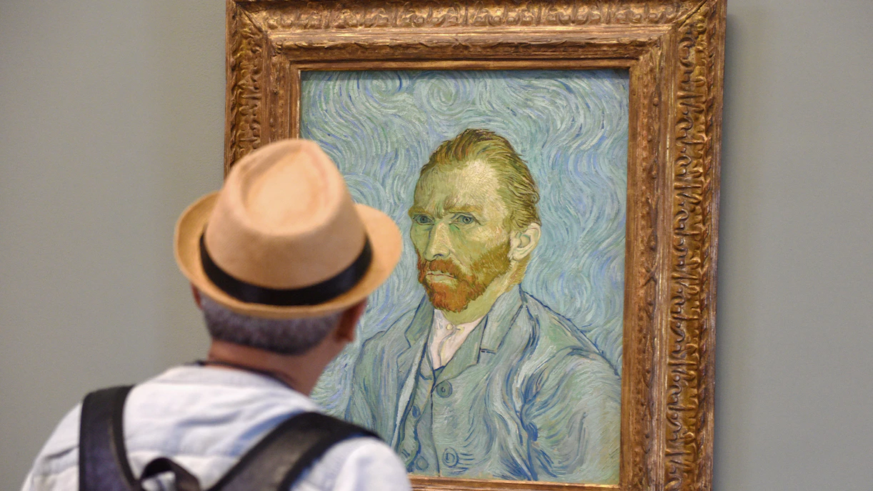 Visitor viewing Van Gogh self-portrait at Van Gogh Museum, Amsterdam, on guided tour.