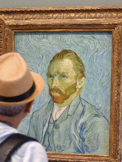 Visitor viewing Van Gogh self-portrait at Van Gogh Museum, Amsterdam, on guided tour.
