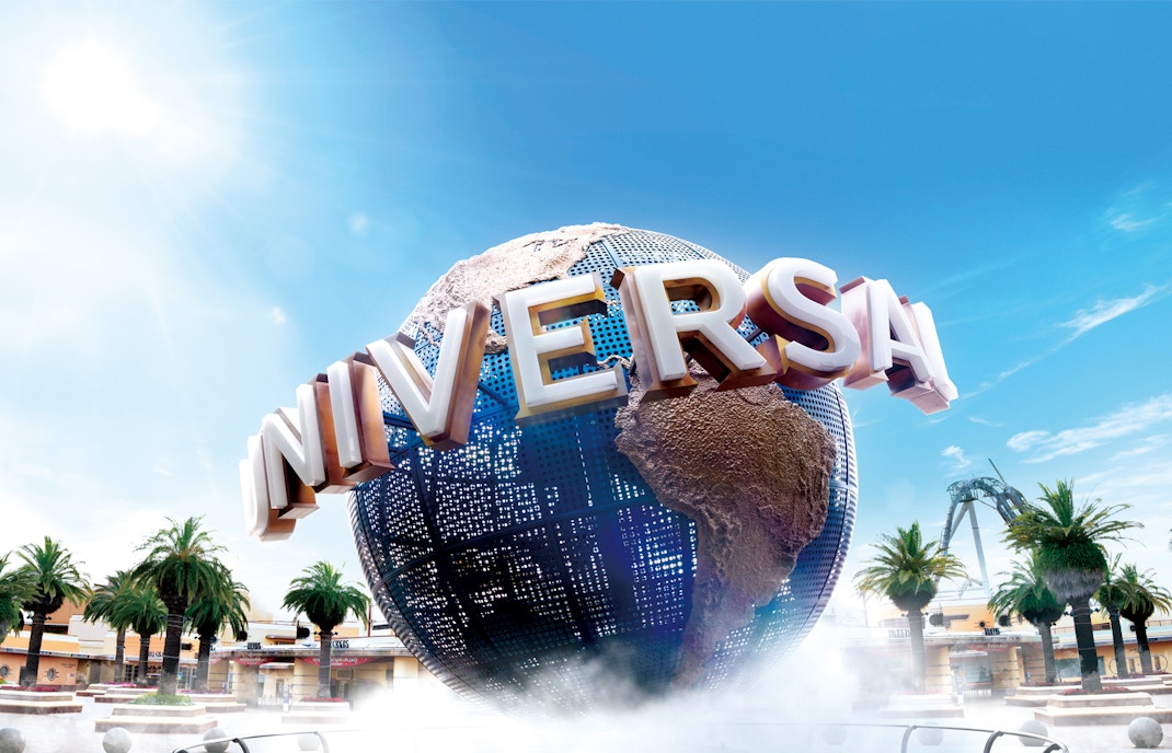 Universal Studios Japan globe with palm trees and roller coaster in background.