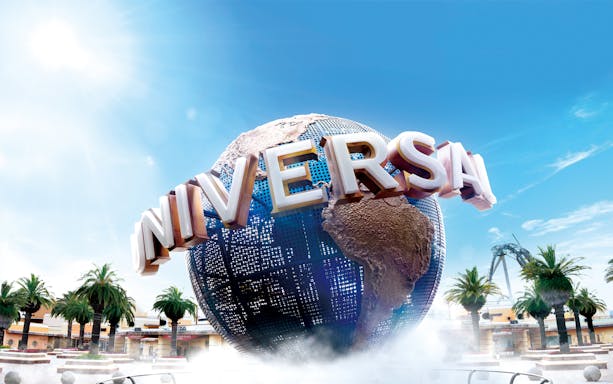 Universal Studios Japan globe with palm trees and roller coaster in background.