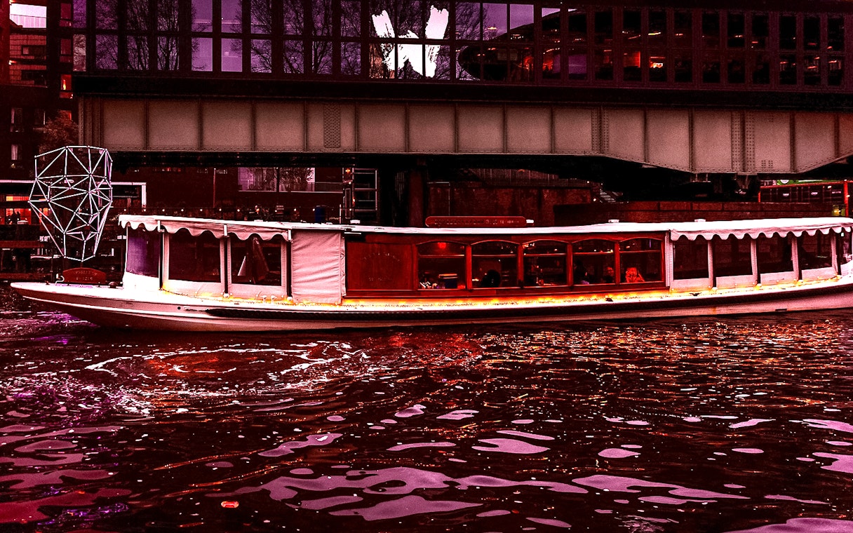 Luxury boat cruising under a bridge during Amsterdam Light Festival.