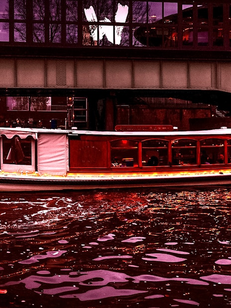 Luxury boat cruising under a bridge during Amsterdam Light Festival.