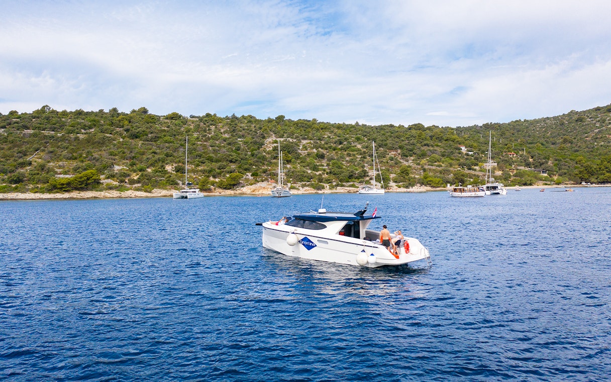 Boat cruising near Duga Bay with lush hills in the background, part of the Small Group 3 Islands tour.