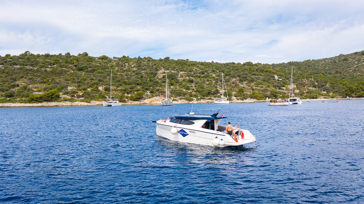 Boat cruising near Duga Bay with lush hills in the background, part of the Small Group 3 Islands tour.