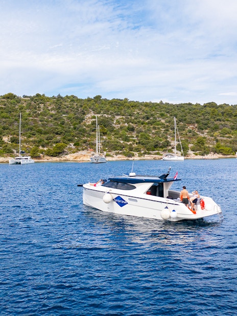 Boat cruising near Duga Bay with lush hills in the background, part of the Small Group 3 Islands tour.