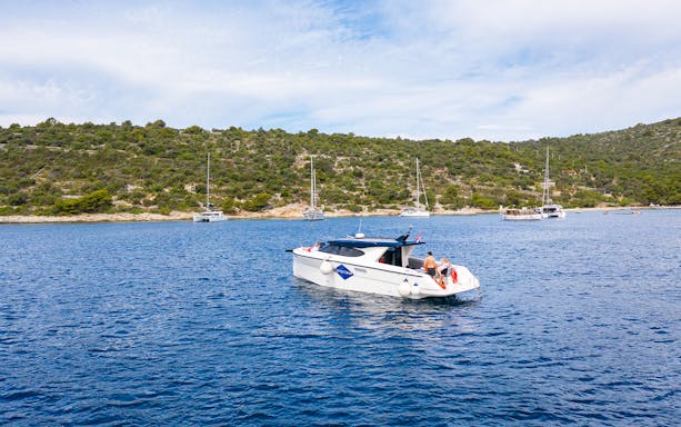 Boat cruising near Duga Bay with lush hills in the background, part of the Small Group 3 Islands tour.