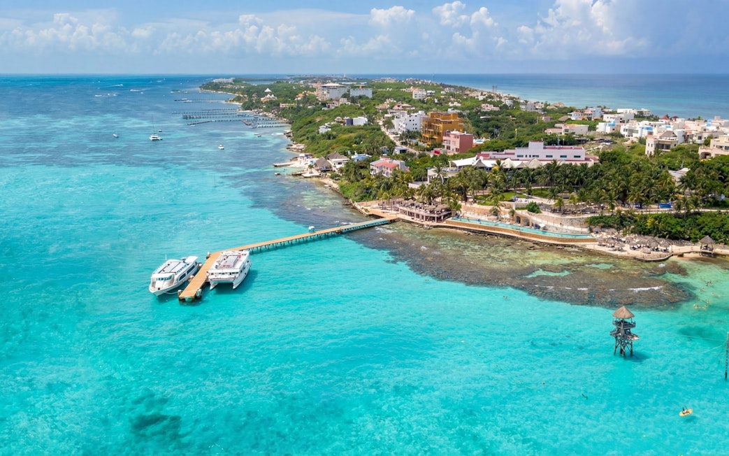 Aerial view of Isla Mujeres island’s main town with turquoise waters and docked boats.