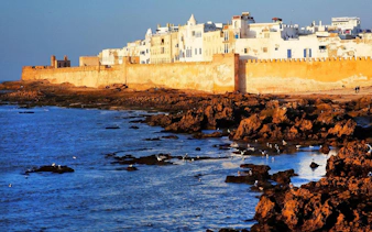 Essaouira city walls along the rocky coastline at sunset, Morocco.