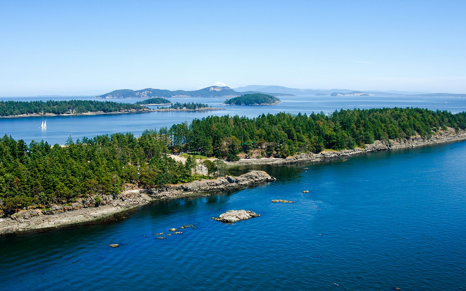 Vancouver Island coastline with Southern Gulf Islands in the background, featuring lush greenery and calm ocean waters.