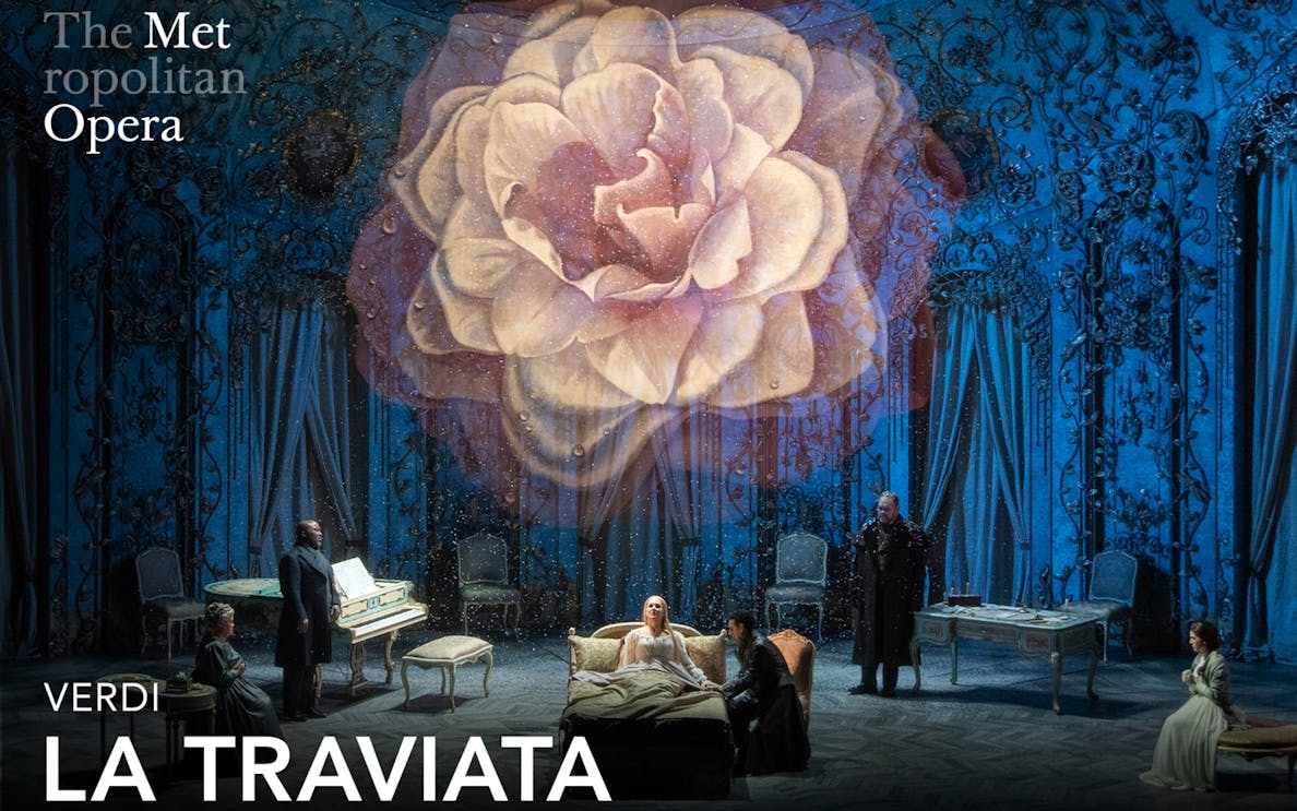 Opera scene from La Traviata at the Metropolitan Opera with a large flower backdrop.