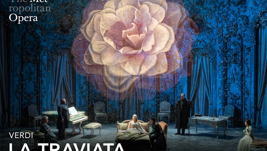 Opera scene from La Traviata at the Metropolitan Opera with a large flower backdrop.