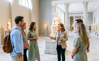 Tour group with guide at National Archaeological Museum, Athens, near ancient statue.