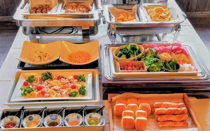 Buffet spread with assorted dishes on Mount Fuji Day Tour, featuring fresh vegetables and bread rolls.