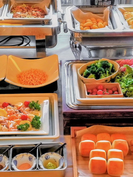 Buffet spread with assorted dishes on Mount Fuji Day Tour, featuring fresh vegetables and bread rolls.