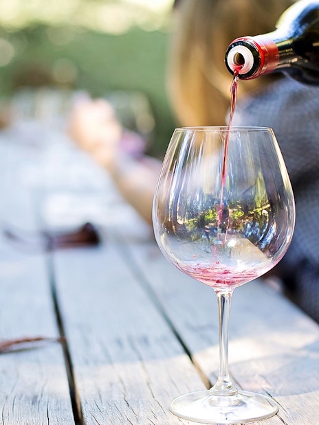 Wine being poured into a glass on a wooden table during Mount Etna tour.