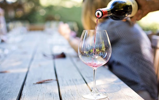 Wine being poured into a glass on a wooden table during Mount Etna tour.