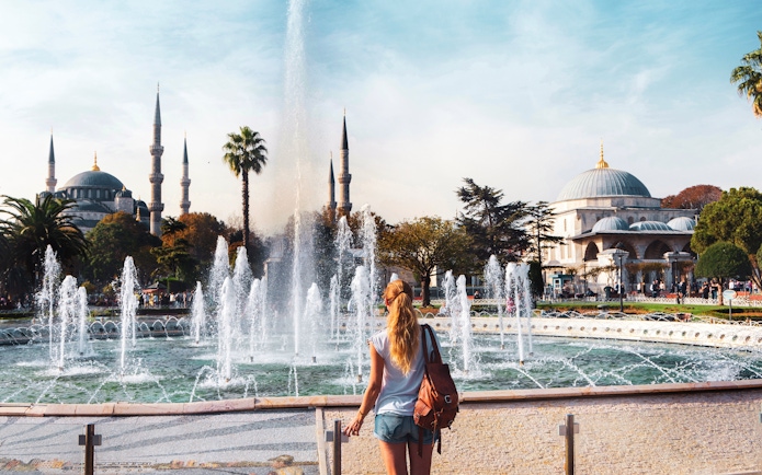 Traveler at fountain in Sultanahmet Square with Blue Mosque in Istanbul.