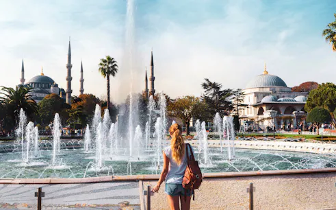 Traveler at fountain in Sultanahmet Square with Blue Mosque in Istanbul.