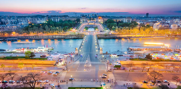 View of Paris from the Eiffel Tower during the light show, overlooking the Seine River and Trocadéro Gardens.