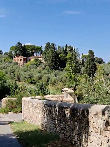 Vespa riders on a scenic road through Tuscany's countryside near Florence.