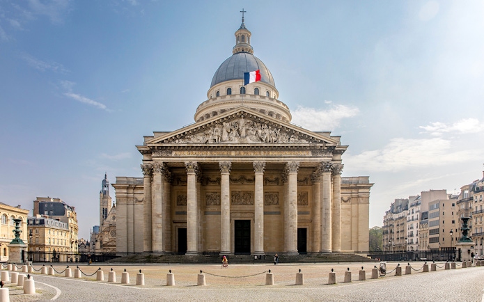 Facade of the Pantheon in Paris with French flag atop dome.