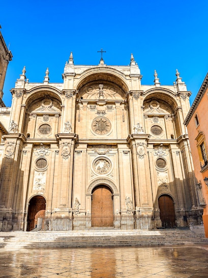 Granada Cathedral facade with ornate carvings and large wooden doors.