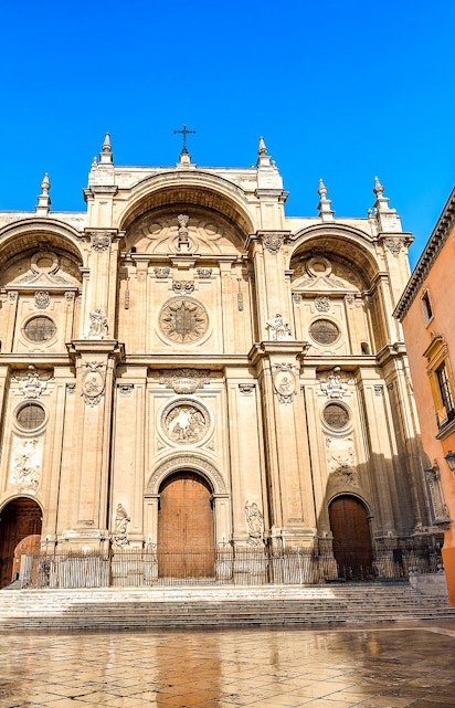 Granada Cathedral facade with ornate carvings and large wooden doors.