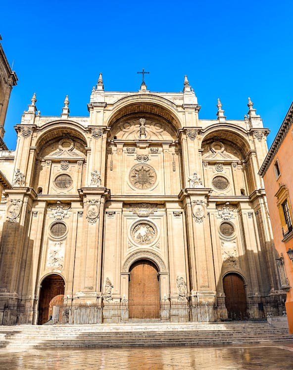 Granada Cathedral facade with ornate carvings and large wooden doors.