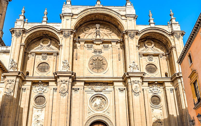 Granada Cathedral facade with ornate carvings and large wooden doors.