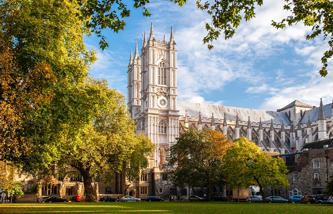 Westminster Abbey in London surrounded by trees on a sunny day.