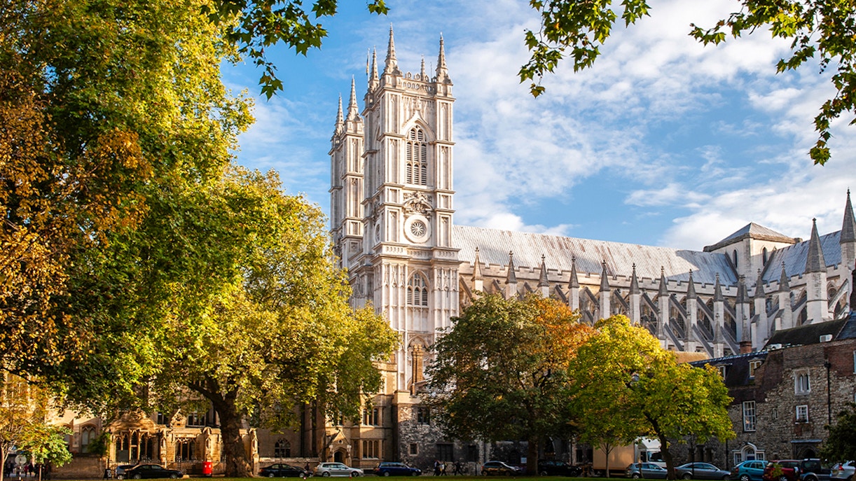 Westminster Abbey in London surrounded by trees on a sunny day.
