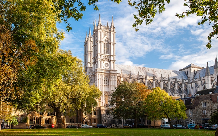 Westminster Abbey in London surrounded by trees on a sunny day.