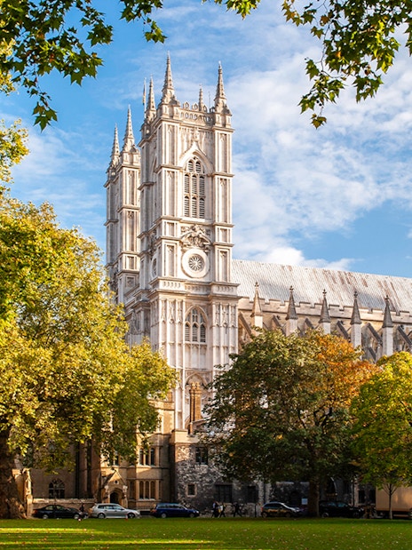 Westminster Abbey in London surrounded by trees on a sunny day.