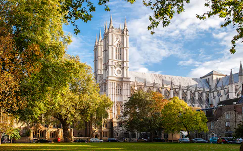 Westminster Abbey in London surrounded by trees on a sunny day.